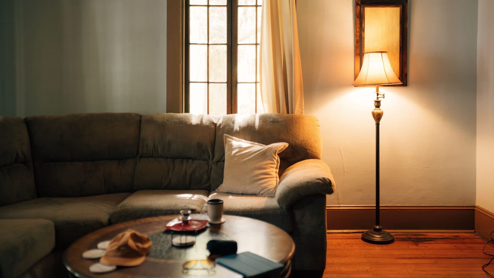 A lamp-lit living room in a house, with a sofa and a low table.